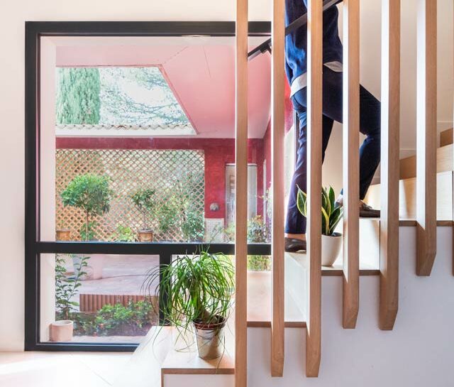 Une femme monte l'es escalier en bois de sa villa tout juste rénovée.
