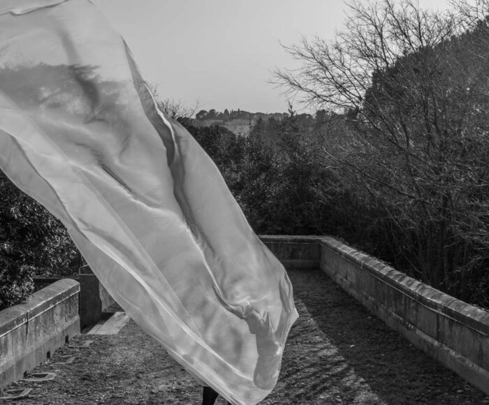 un grand voile blanc s'envole, cachant un homme dans la nature