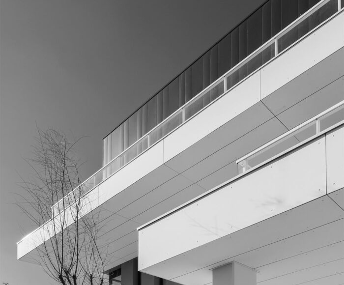 Photographie d'architecture à Montpellier. La belle lumière en noir et blanc du soleil jouant sur les parois blanches et anguleuse d'un immeuble moderne de bureaux.