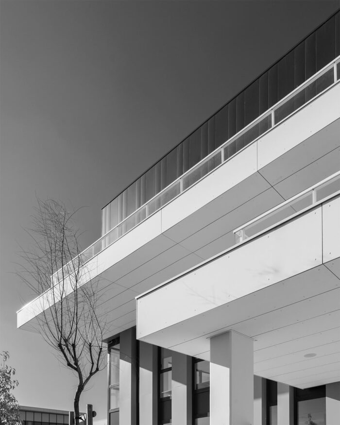 Photographie d'architecture à Montpellier. La belle lumière en noir et blanc du soleil jouant sur les parois blanches et anguleuse d'un immeuble moderne de bureaux.