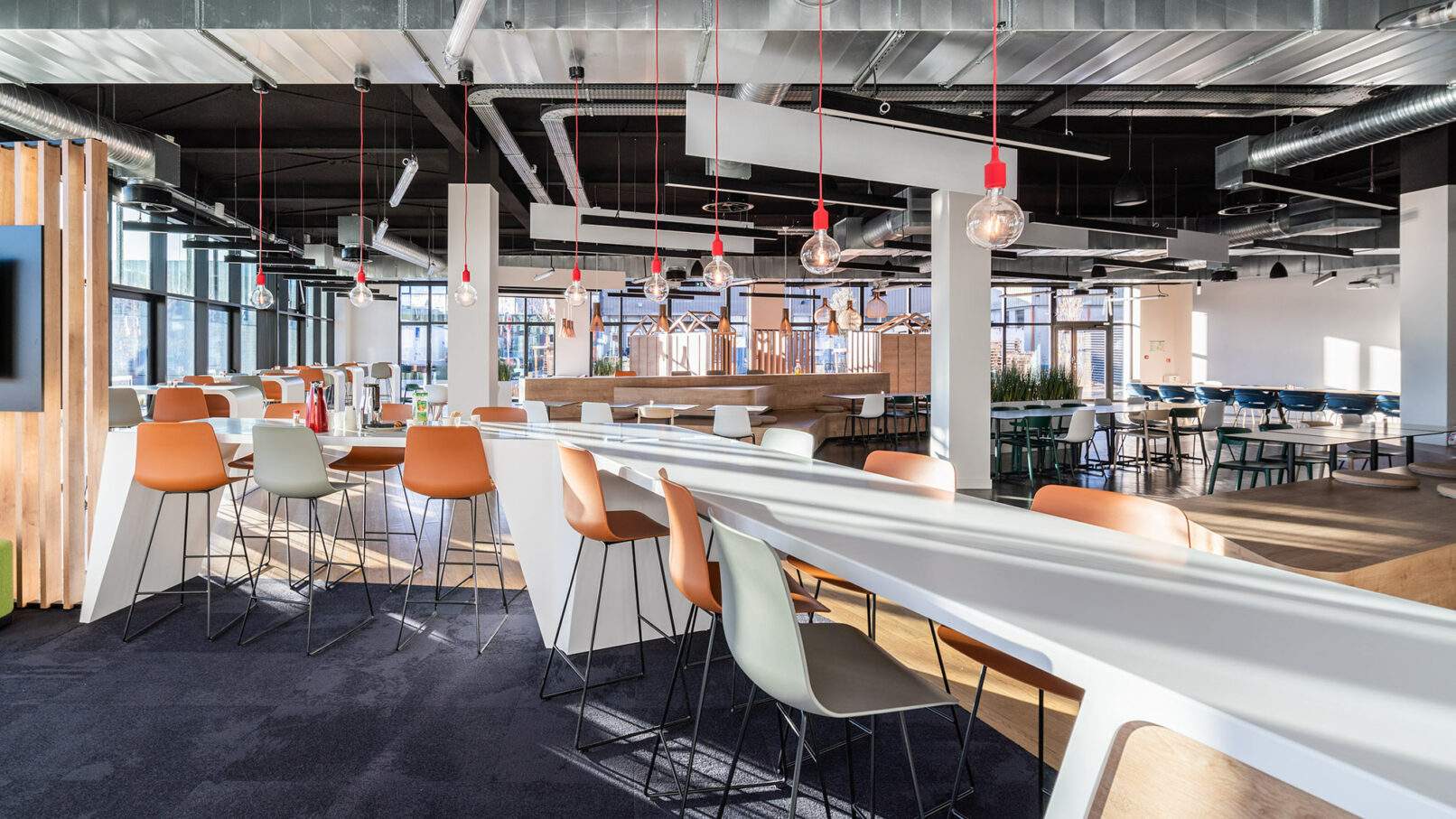 Image d'une grande table blanche entourée de chaises dans une grande pièce. La table est située dans le restaurant du siège social d'Aldes, une entreprise française spécialisée dans la ventilation et la climatisation.